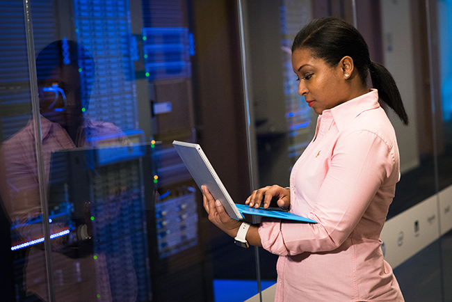adult-african-american-woman-business-city-1181341 African American technologist working in a server room.